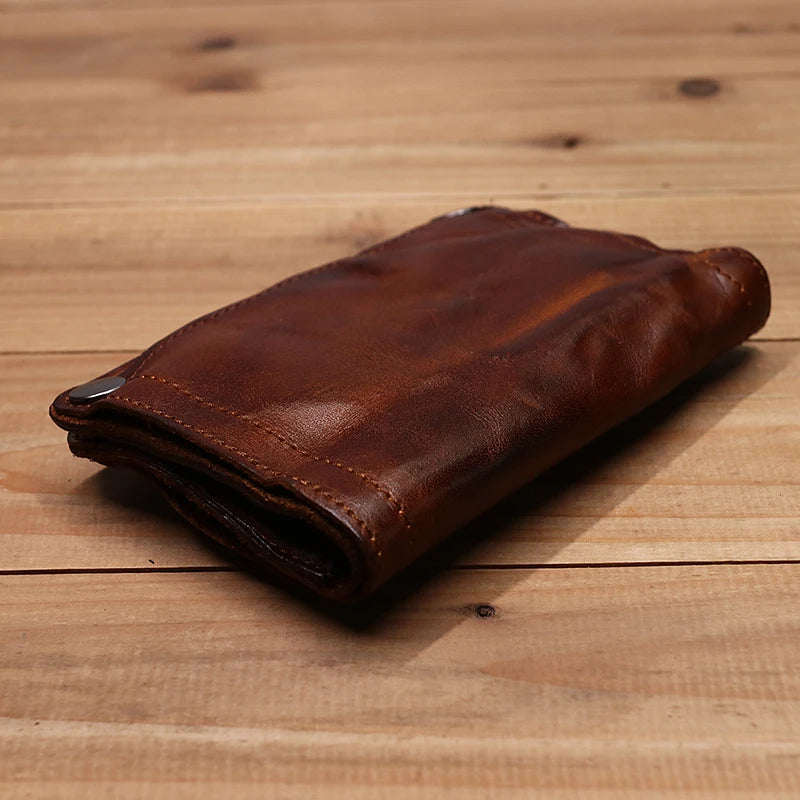 Dunkelbraunes Vintage-Leder-Bifold-Wallet auf einer hellen Holzoberfläche.