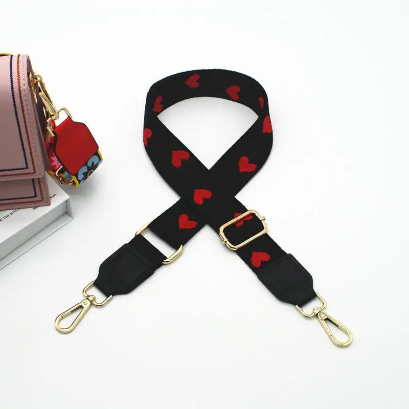 Sangle d'épaule noire ajustable avec un motif de cœurs rouges sur un sac en toile.