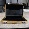 A gold-colored aluminum case for holding credit cards and IDs, shown open on a wooden surface.