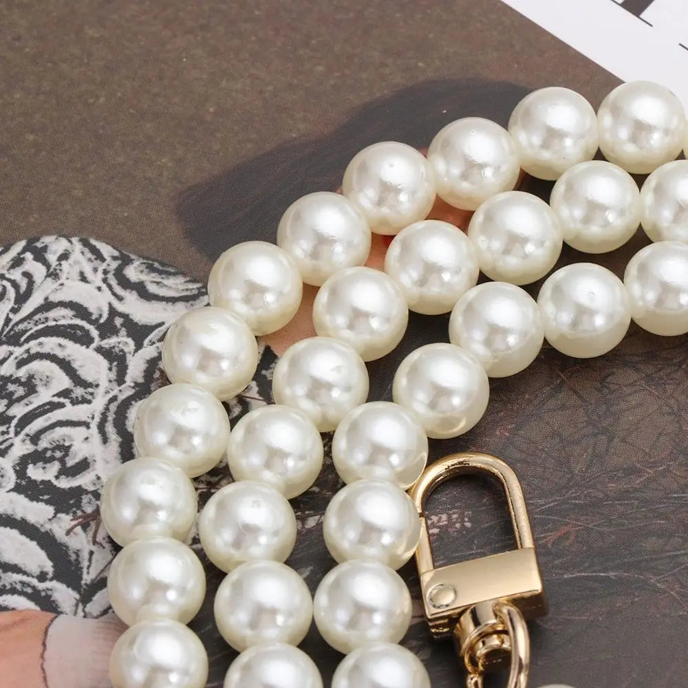 A gold-toned pearl strap for a handbag or purse, featuring multiple round pearls.