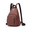 A brown canvas backpack with black straps and a zipper pocket is shown against a white background.