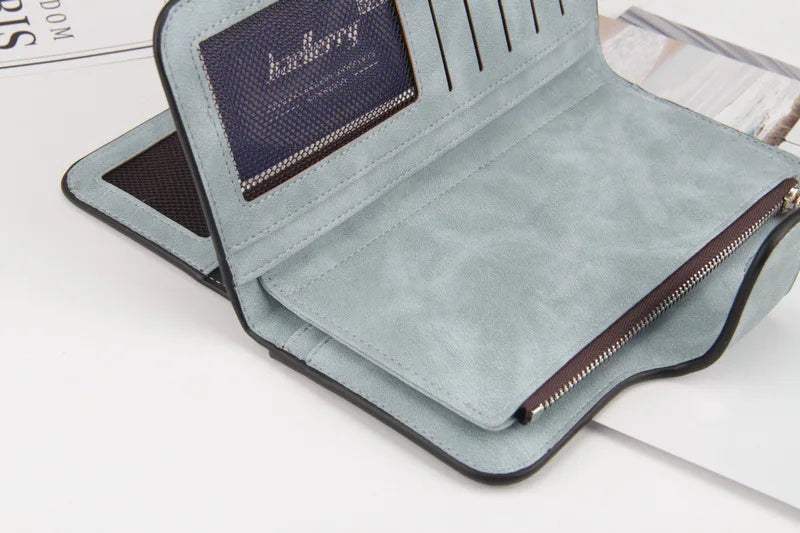 A light blue card holder wallet with a dark brown leather accent and a zippered closure is shown on a white surface.