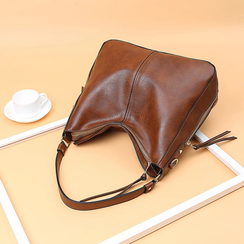 A brown vintage faux leather hobo shoulder bag lying on a light beige surface.