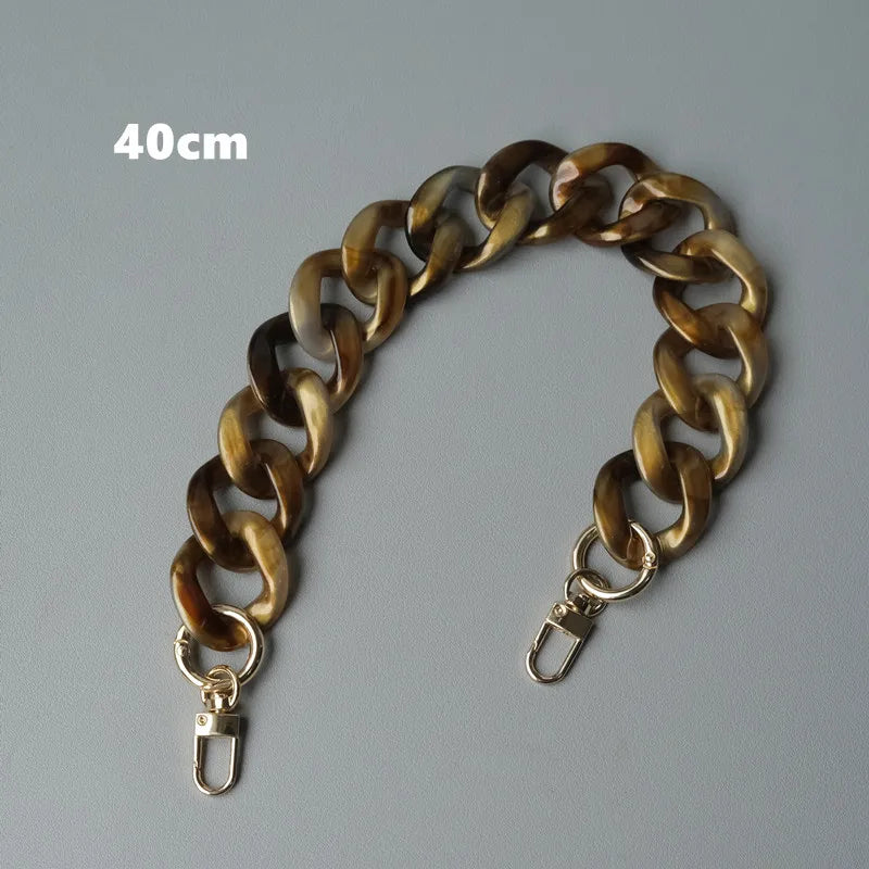Bolsa de hombro de resina tono dorado, mide 40cm, mostrada contra un fondo gris.