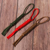 Three paracord keychains in green, red, and brown are displayed on a wooden surface.
