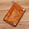 Braunes Leder-Bifold-Wallet mit silbernen Schnallen auf einer Holzoberfläche.
