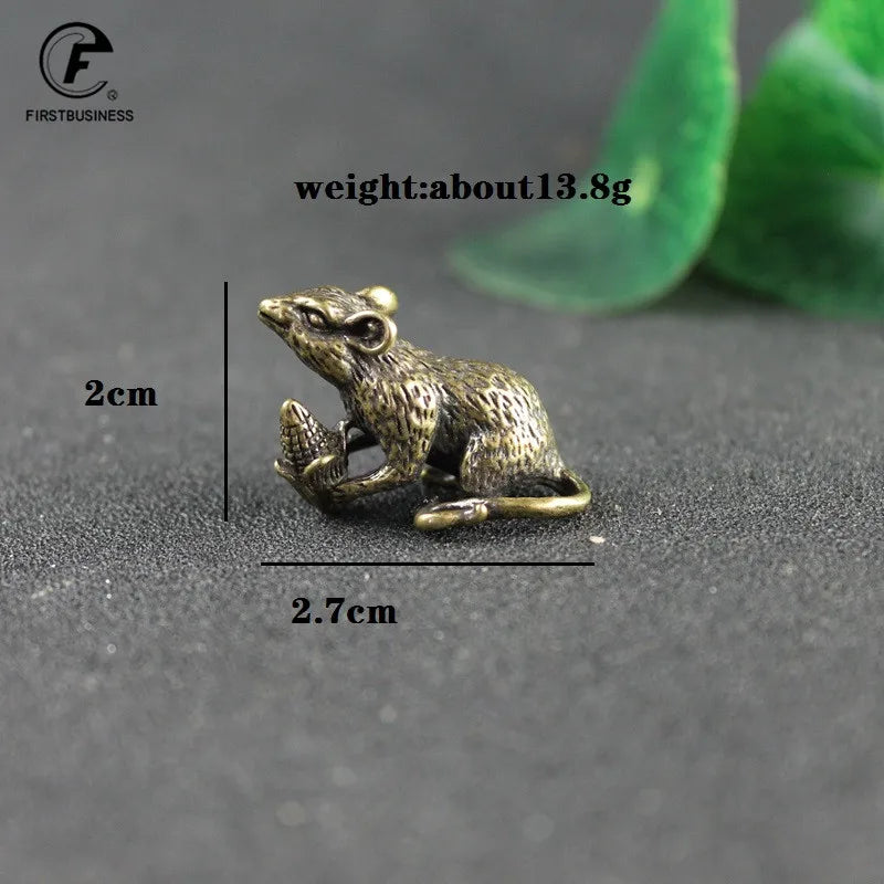 A vintage brass rat figurine is shown against a dark background with measurement lines.