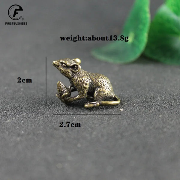 A vintage brass rat figurine is shown against a dark background with measurement lines.