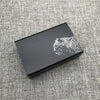 A black custom engraved cigarette case featuring a silver leopard print design on a textured gray fabric.