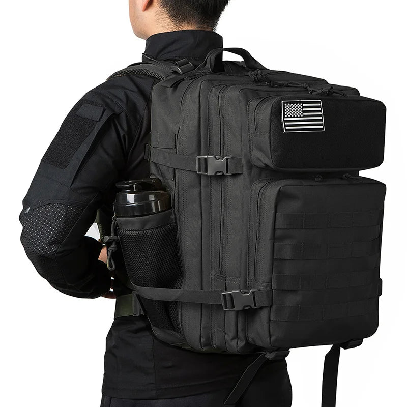 A black tactical backpack with a MOLLE system and laptop compartment is shown from the back.