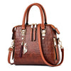 A brown crocodile-embossed leather tassel shoulder bag with gold hardware and a brown strap.