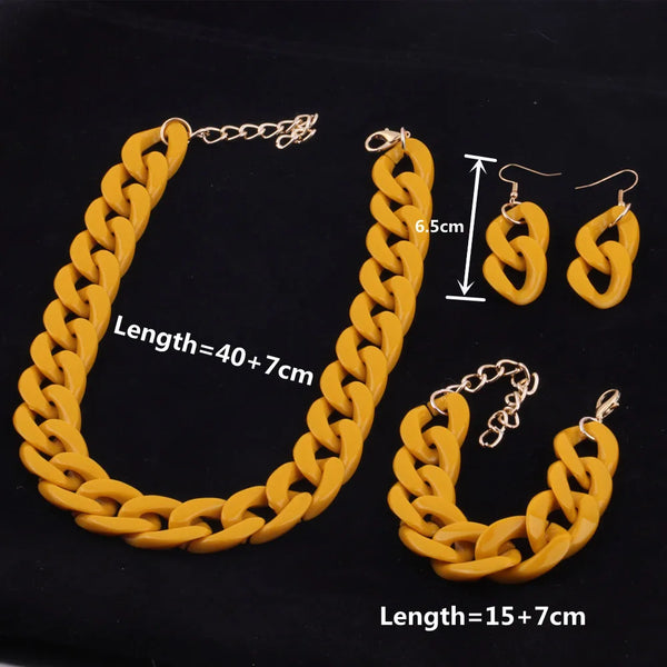 A set of yellow resin acrylic necklaces and earrings with chain components shown against a black background.