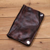 Dunkelbraunes Leder-Bifold-Wallet mit gestickten Kanten und silbernen Schnallen auf Holz