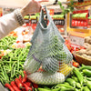 A reusable organic cotton mesh grocery tote bag filled with fresh vegetables and produce.