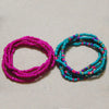 Two strands of colorful belly bead chains, one magenta and one turquoise, laid out on a light background.