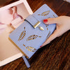 Cartera clutch de cuero PU azul claro con detalles en hoja de oro, sostenida por una mano sobre una superficie de madera junt