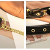 A close-up of a black PU leather crossbody sling bag with gold hardware and a tan fabric background.