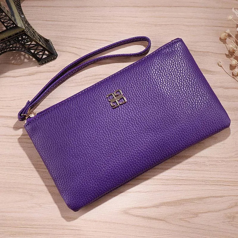Cartera con cremallera de cuero PU morada con logo dorado sobre una superficie de madera clara.
