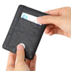 A hand is inserting a credit card into a black leather wallet to demonstrate its slim design.
