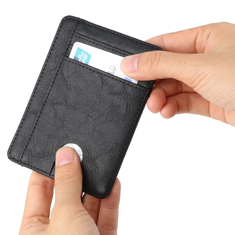 A hand is inserting a credit card into a black leather wallet to demonstrate its slim design.