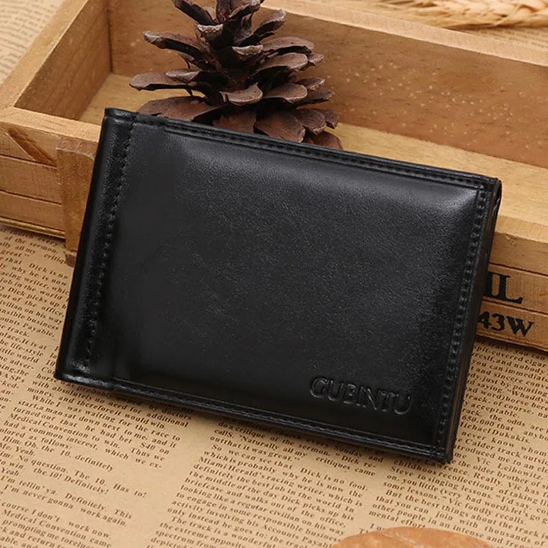 A black men's leather money clip wallet resting on a wooden surface next to a pinecone.