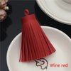 A set of red leather tassel fringe craft supplies displayed on a white plate.