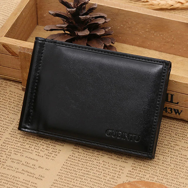 A black men's leather money clip wallet resting in a wooden box next to a pinecone.