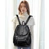 A woman wearing a black vintage soft leather backpack and a cream turtleneck sweater.