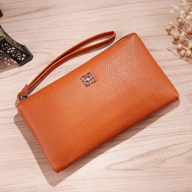 Cartera con cremallera de cuero PU marrón y correa de cuero sobre una superficie de madera clara.