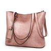 A dusty rose waxed leather bucket bag with dual straps shown from the front.