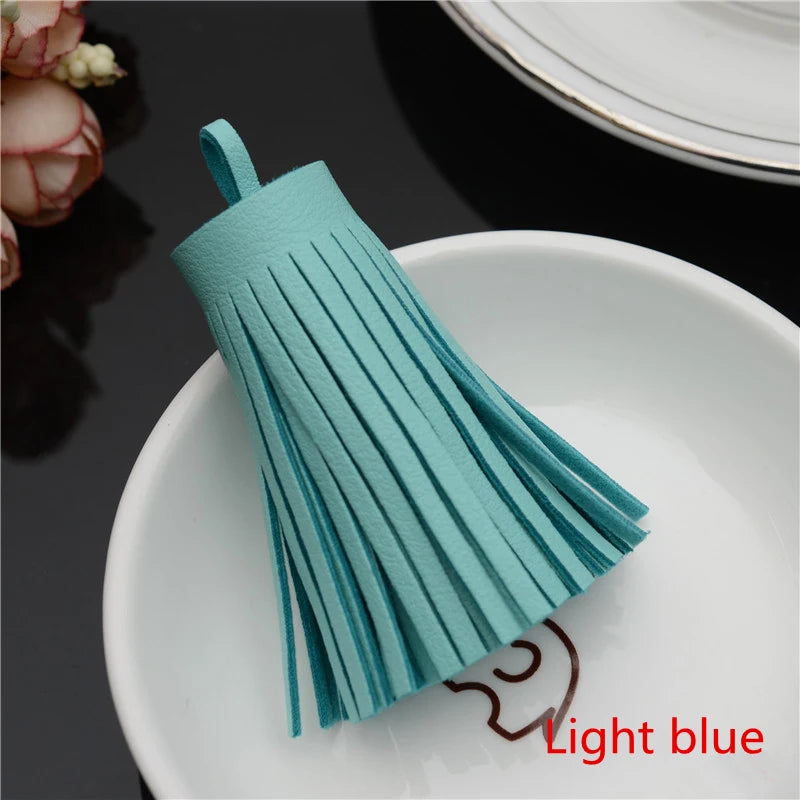 A teal leather tassel fringe craft supply set displayed on a white plate.