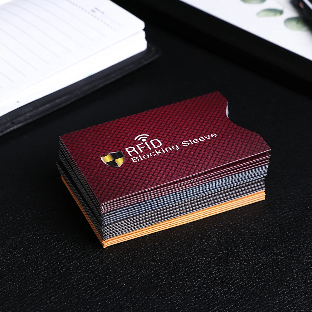 A stack of maroon RFID blocking card sleeves is placed on a black surface.