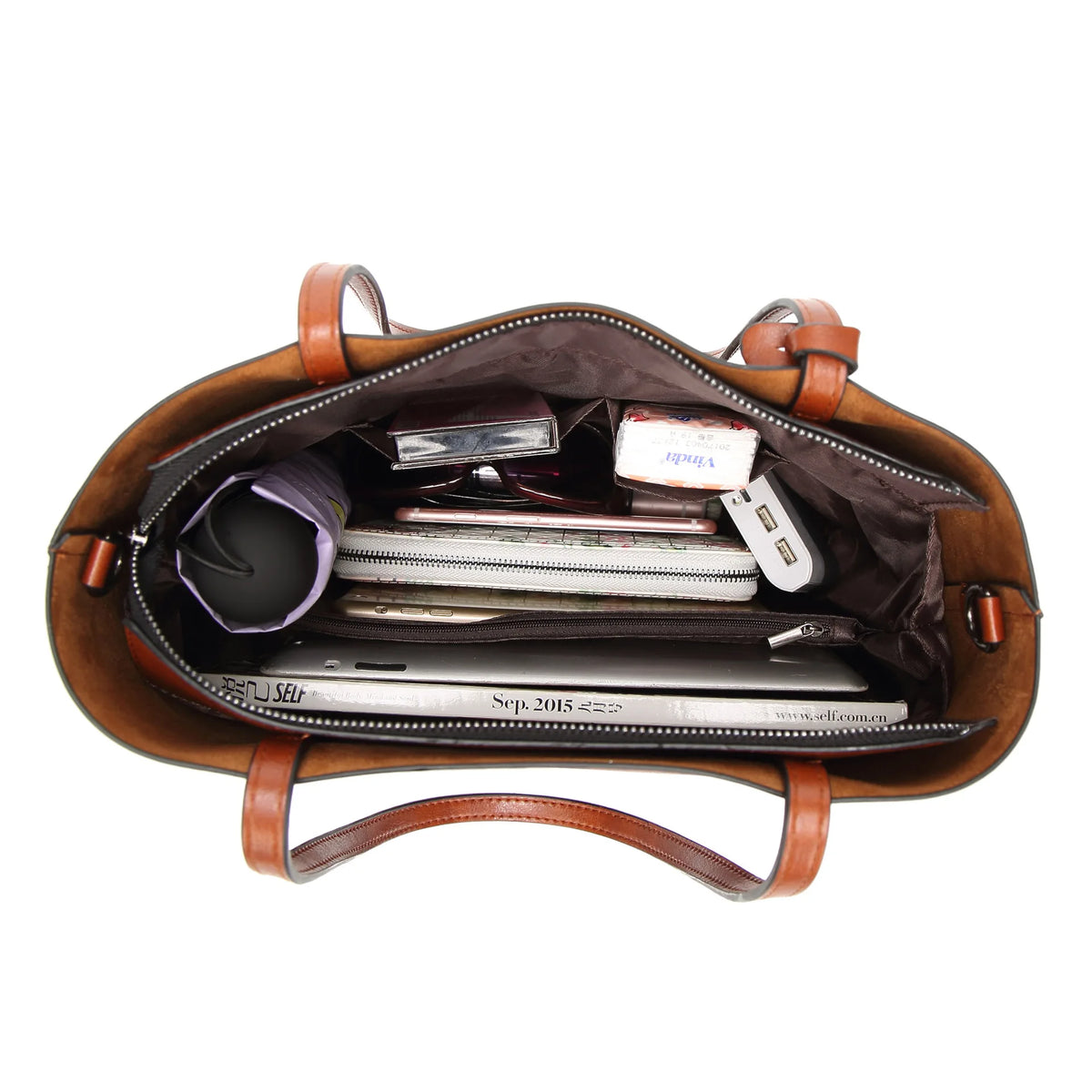 A brown waxed leather bucket bag with dual straps is shown open, revealing various electronic accessories inside.