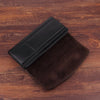 Portefeuille de téléphone en cuir marron foncé avec une pince ceinture noire, posé sur une surface en bois.