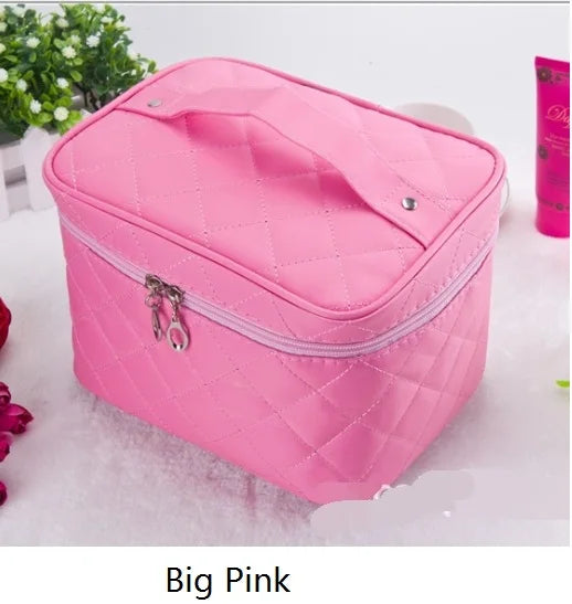 A pink quilted cosmetic storage box with a zipper and hanging charm is shown on a white surface.