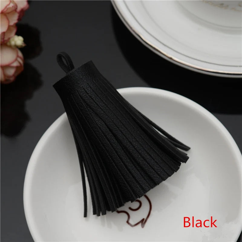 A black leather tassel fringe craft supplies set resting on a white plate.