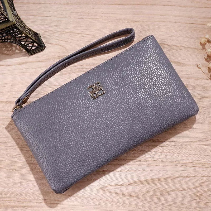Cartera con cremallera de cuero PU gris y correa de cuero sobre una superficie de madera.