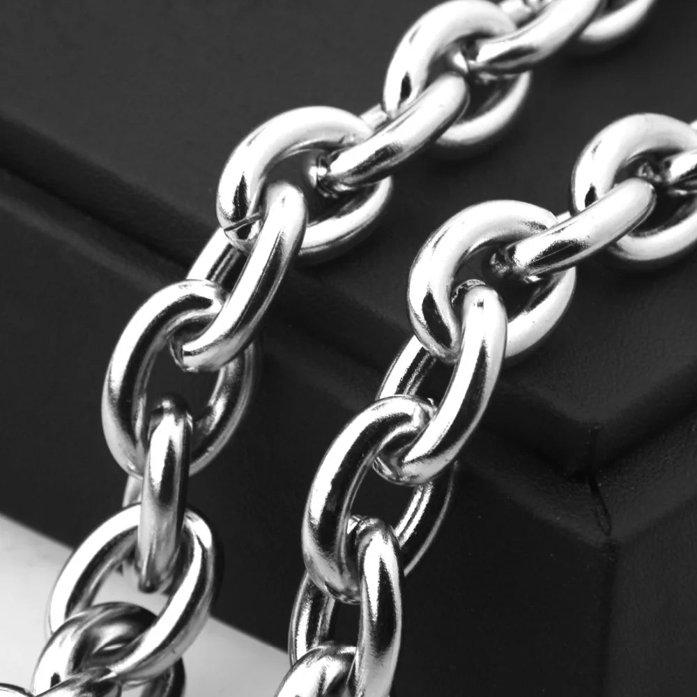 A close-up shot of a silver stainless steel rolo link chain necklace lying on a dark surface.