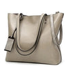 A beige waxed leather bucket bag with dual straps shown from the front.