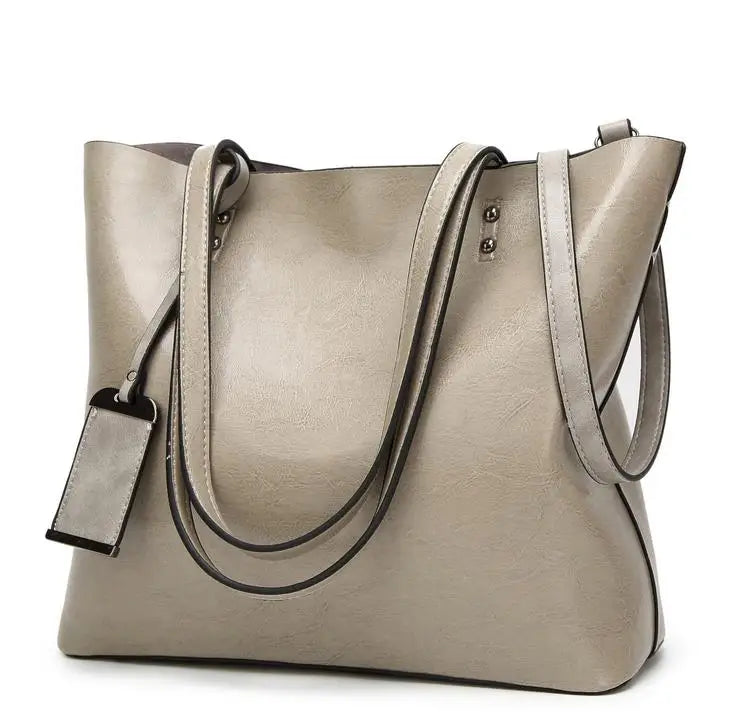 A beige waxed leather bucket bag with dual straps shown from the front.