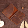 A brown genuine leather passport wallet with card holders resting on a dark woven fabric.