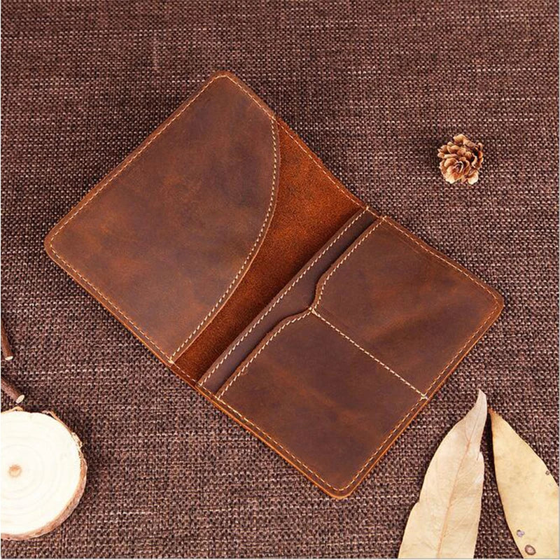 A brown genuine leather passport wallet with card holders resting on a dark woven fabric.