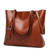 A brown waxed leather bucket bag with dual straps shown from the front.