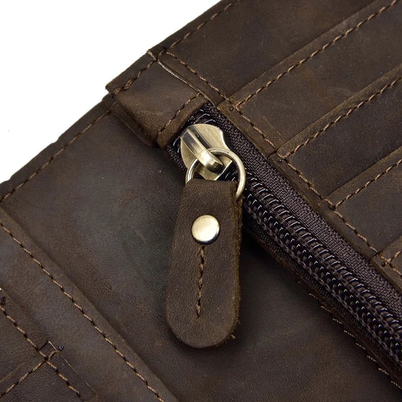 Close-up of a brown leather bifold wallet featuring a stitched zipper and a brass metal chain closure.