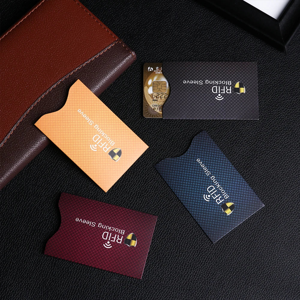 A collection of various colored RFID blocking card sleeves displayed on a dark surface.