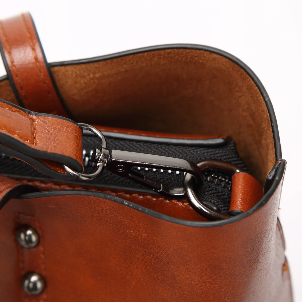 Close-up of a brown waxed leather bucket bag showing the top edge and dual strap closure.