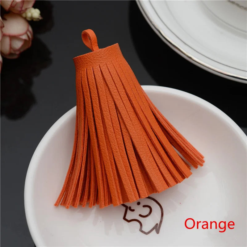 Orange leather tassel fringe craft supplies set displayed on a white plate.