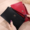 Cartera con cremallera de cuero sintético negro junto a una cartera de cuero sintético rojo sobre una superficie de madera.