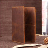 A brown genuine leather passport wallet with card holders shown in a vertical angle on a dark surface.