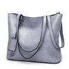 A light gray waxed leather bucket bag with dual straps shown from the front.